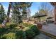Stone patio with a fountain, lush landscaping, built-in brick grill, and dining area at 29 Viking Dr, Cherry Hills Village, CO 80113