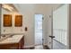 Bright bathroom with wood cabinets, sleek fixtures, and doorway leading to carpeted room at 8898 W Plymouth Ave, Littleton, CO 80128