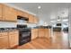 Bright kitchen featuring wooden cabinetry, black appliances, stone counters, and an open layout at 18947 E 57Th Pl, Denver, CO 80249