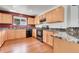 Well-lit kitchen boasting wooden cabinets, black appliances, granite counters, and wood flooring at 18947 E 57Th Pl, Denver, CO 80249