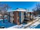 Exterior view of condo building, with brick and stucco exterior, balconies and snow at 12143 Melody Dr # 104, Denver, CO 80234