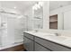 Clean bathroom featuring a double sink vanity, large mirror, and walk-in shower with glass doors at 27424 E Byers Ave, Aurora, CO 80018