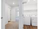 Well-lit laundry room with wood floor, washer, dryer, and hallway views at 27424 E Byers Ave, Aurora, CO 80018