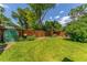 Spacious backyard showcasing a well-maintained lawn, a green house, and a tall wooden fence for privacy at 1410 S Ammons St, Lakewood, CO 80232