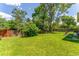 Large backyard featuring a lush green lawn, mature trees, and a wooden privacy fence, offering a tranquil outdoor space at 1410 S Ammons St, Lakewood, CO 80232