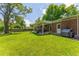 Expansive backyard featuring a lush lawn, covered patio, a grill, and mature trees, perfect for outdoor enjoyment at 1410 S Ammons St, Lakewood, CO 80232