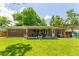 Brick home featuring an expansive backyard with a covered patio, trees, and green lawn at 1410 S Ammons St, Lakewood, CO 80232