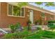 Charming front entry of a brick home, featuring lush landscaping and decorative flower pots at 1410 S Ammons St, Lakewood, CO 80232