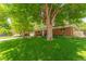 A well-maintained front yard with mature trees adds character to this inviting brick home at 1410 S Ammons St, Lakewood, CO 80232