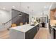 Open-concept kitchen with quartz island, pendant lighting, and hardwood floors with stairwell feature at 3047 S Cherokee St, Englewood, CO 80110