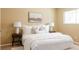 Bright bedroom with a white comforter, two side tables, lamps and a neutral-colored picture on the wall at 654 S Xenon Ct, Lakewood, CO 80228