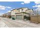 Tan two-story townhouse with a two-car garage and a gray driveway on a partly cloudy day at 2184 Willow Ct, Denver, CO 80238