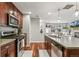 Bright kitchen area with stainless steel appliances, island sink, dark wood cabinets, and access to the living room at 2184 Willow Ct, Denver, CO 80238