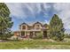Stunning two-story home with a well-manicured lawn and mature trees under a partly cloudy sky at 6411 Sand Rose Ct, Castle Rock, CO 80108
