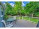 A well-maintained backyard with a gray deck, green lawn, mature trees, and white fencing for privacy at 6368 S Harlan Way, Littleton, CO 80123