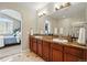 Bright bathroom featuring double sinks, marble counters, tile flooring and an arched doorway to the bedroom at 10103 Bluffmont Ln, Lone Tree, CO 80124