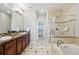Well-lit bathroom featuring tile flooring, separate shower and soaking tub, and and sinks at 10103 Bluffmont Ln, Lone Tree, CO 80124