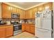 Well-lit kitchen featuring wooden cabinets, stainless steel appliances, and a stylish tile backsplash at 18619 E Vassar Dr, Aurora, CO 80013