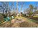 Lush backyard featuring an outdoor stone firepit and three blue chairs beneath mature trees at 6755 W 33Rd Ave, Wheat Ridge, CO 80033