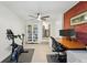 Functional home office featuring brick accent wall, modern desk, computer setup, bookshelf, and fitness equipment at 6755 W 33Rd Ave, Wheat Ridge, CO 80033