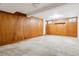 A basement with paneled walls, carpeted floors, complemented by a built-in shelf and windows at 869 S Williams St, Denver, CO 80209