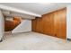 A spacious basement featuring paneled walls, carpeted floors, and access to a staircase at 869 S Williams St, Denver, CO 80209