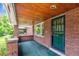 View of the brick porch with brick pillar features, a green screen door and a wooden ceiling at 869 S Williams St, Denver, CO 80209