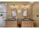 Bathroom showcasing dual sinks with wood vanities, granite countertops, and modern lighting fixtures at 6802 Poppy Ct, Arvada, CO 80007