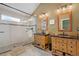Bathroom with a glass shower, double sinks, wooden vanities, and decorative mirrors at 6802 Poppy Ct, Arvada, CO 80007