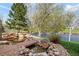 Beautiful backyard pond with rock features, landscaping, and a lush lawn, set against a blue sky at 6802 Poppy Ct, Arvada, CO 80007
