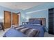 Bedroom with blue walls, two closets, a wood-framed bed, and a gray and brown blanket at 9208 W 100Th Pl, Broomfield, CO 80021