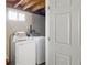 A laundry room with a modern washing machine, dryer, and small window in an unfinished basement at 6167 Newland St, Arvada, CO 80003