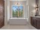 Bright bathroom features soaking tub with large window overlooking a wooded lot at 1207 Wildcat Bend Ct, Castle Rock, CO 80108