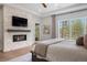 Main bedroom featuring a stone fireplace, TV, and light-filled windows with an outdoor view at 1207 Wildcat Bend Ct, Castle Rock, CO 80108