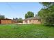 Expansive backyard with mature trees, a brick home, a wooden shed, and a spacious patio at 981 Ursula St, Aurora, CO 80011