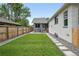 Backyard features manicured lawn, wood fence, stone walkway, and grey painted brick house at 3344 W 33Rd Ave, Denver, CO 80211