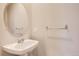 A modern powder room features a round mirror, stylish light fixtures, and a sleek pedestal sink at 7498 W Saratoga Pl, Littleton, CO 80123