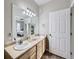 Bathroom featuring dual sinks, a large mirror, and tile flooring, plus a view into the bedroom at 8481 W Union Ave # 4-203, Littleton, CO 80123