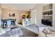 Open-concept living room features a TV, kitchen view, dining table, and modern decor at 8481 W Union Ave # 4-203, Littleton, CO 80123