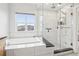 Modern bathroom featuring white tile, a soaking tub, and a separate shower with glass door at 3644 Pinedale St, Boulder, CO 80301