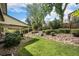 Landscaped backyard featuring a covered patio, lush lawn, and a stone pathway leading to an upper level at 6251 W 74Th Ave, Arvada, CO 80003