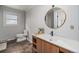 Well-lit bathroom featuring wood-look vanity, modern fixtures, and stylish circular mirror at 6251 W 74Th Ave, Arvada, CO 80003