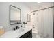 Modern bathroom with sleek black fixtures, a white vanity, and a shower featuring a stylish patterned curtain at 6251 W 74Th Ave, Arvada, CO 80003