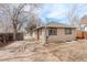 Home exterior showing the yard, detached garage, mature trees, and a basement access point at 2056 Fulton St, Aurora, CO 80010