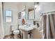 Bright bathroom with pedestal sink, toilet, and window at 1235 Dahlia St, Denver, CO 80220