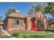 Charming brick home featuring a bright red front door and awning, complemented by lush green lawn and classic shutters at 1235 Dahlia St, Denver, CO 80220