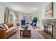 Comfortable living room with a brown leather sofa, two blue chairs, hardwood floors, and a decorative fireplace at 1235 Dahlia St, Denver, CO 80220