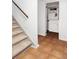 Hallway with staircase leads to a bathroom that features tiled floors and white walls at 2030 Cody St, Lakewood, CO 80215