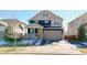 Two-story home with a blend of dark siding and light stone accents, complemented by a well-manicured lawn and a two-car garage at 17548 E 103Rd Dr, Commerce City, CO 80022