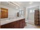 Bathroom with a double sink vanity, dark wood cabinets, and shower with decorative curtains at 7603 Yule Ct, Arvada, CO 80007